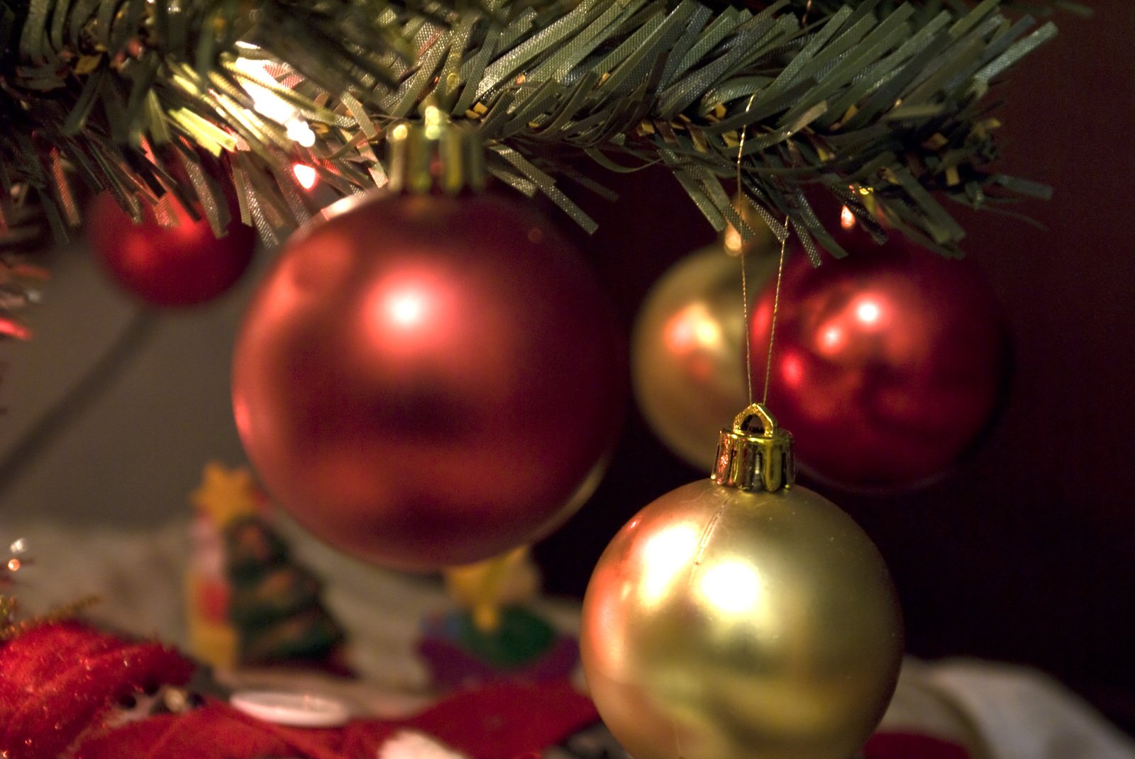 three gold and red ornaments hanging from the christmas tree