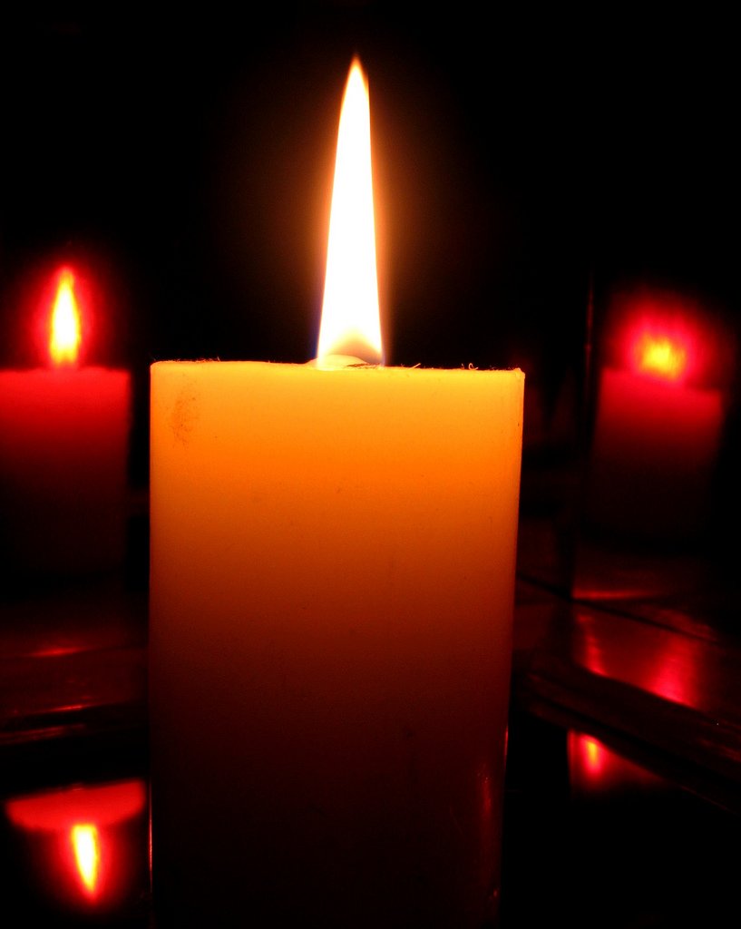 lit candle on a table with four red lights around it