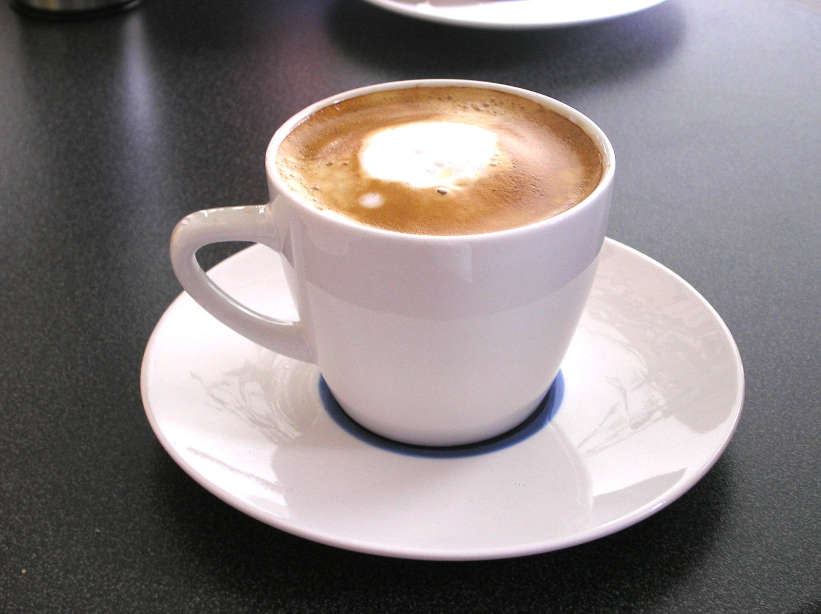a cappuccino sits atop a white saucer on a table