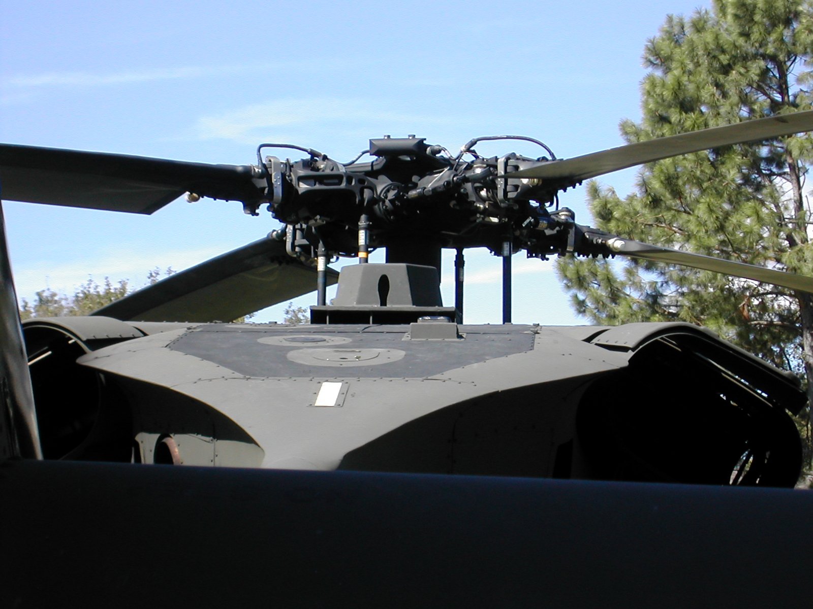 an army helicopter parked outside next to trees