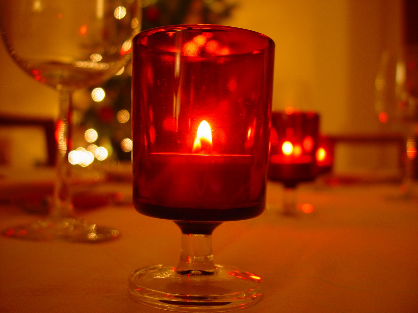 red candles sit in wine glasses on a table