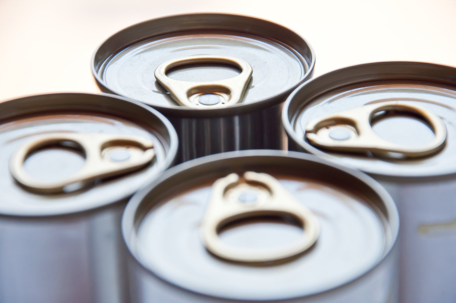 six metal soda cans are in a group with silver lids