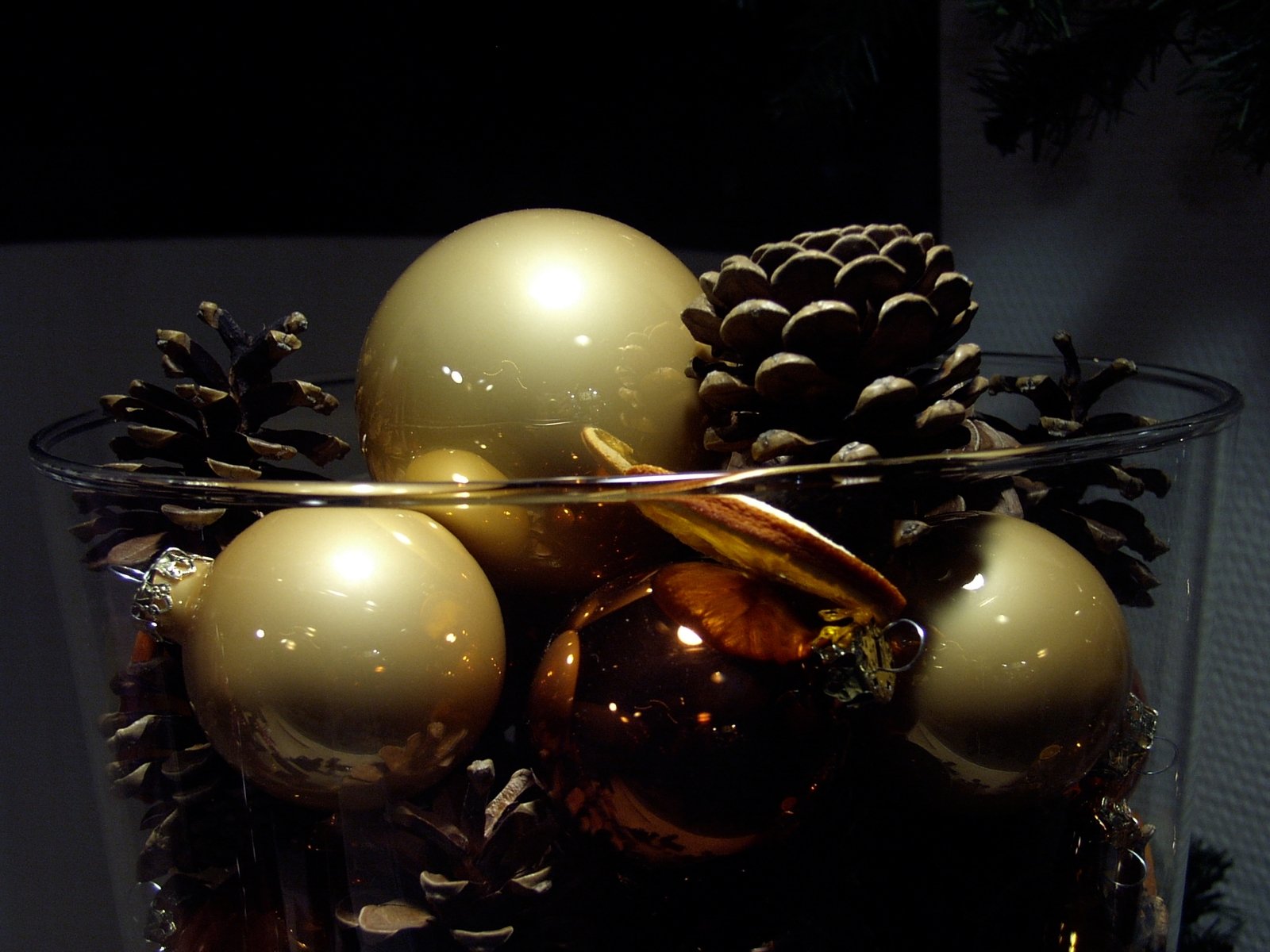 a clear bowl filled with some ornaments next to a christmas tree