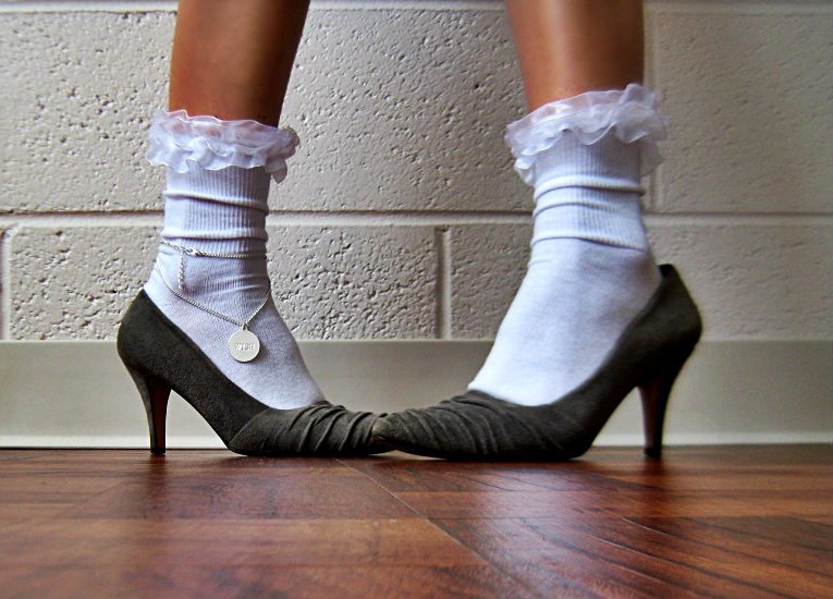 a woman wearing white and grey shoes standing on top of a wood floor