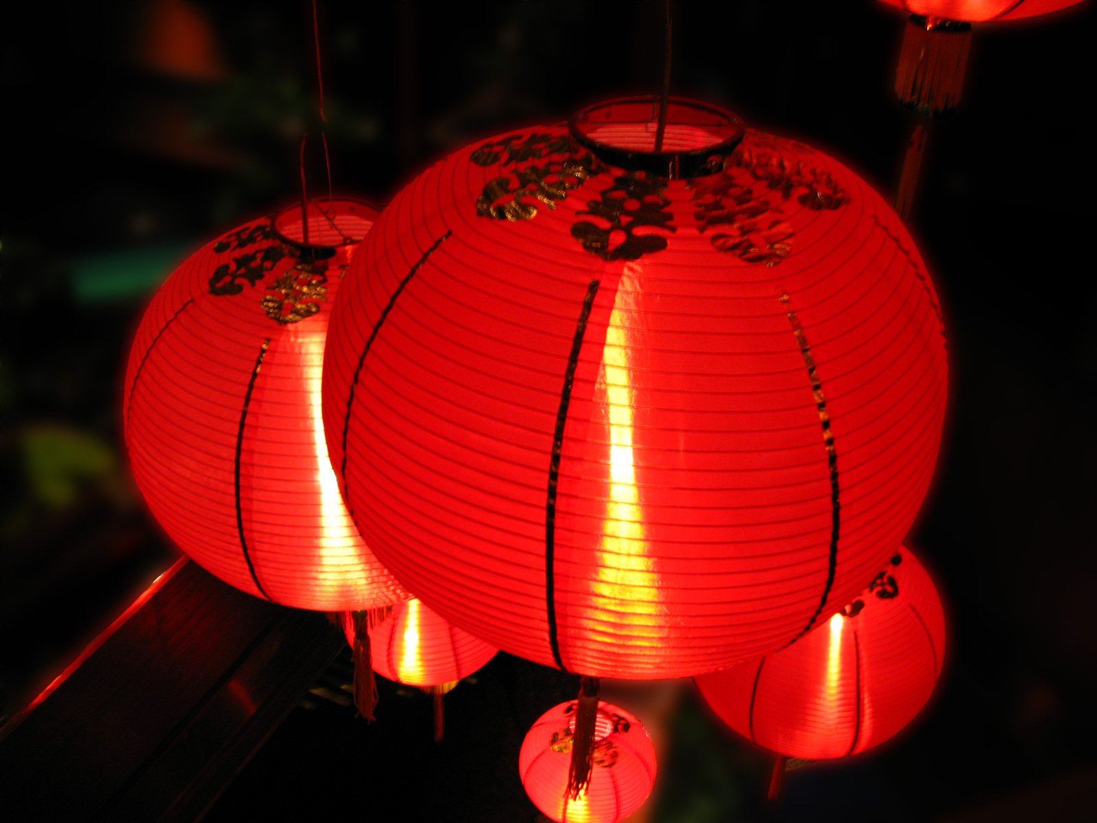 three red chinese lanterns in the dark and some lights on