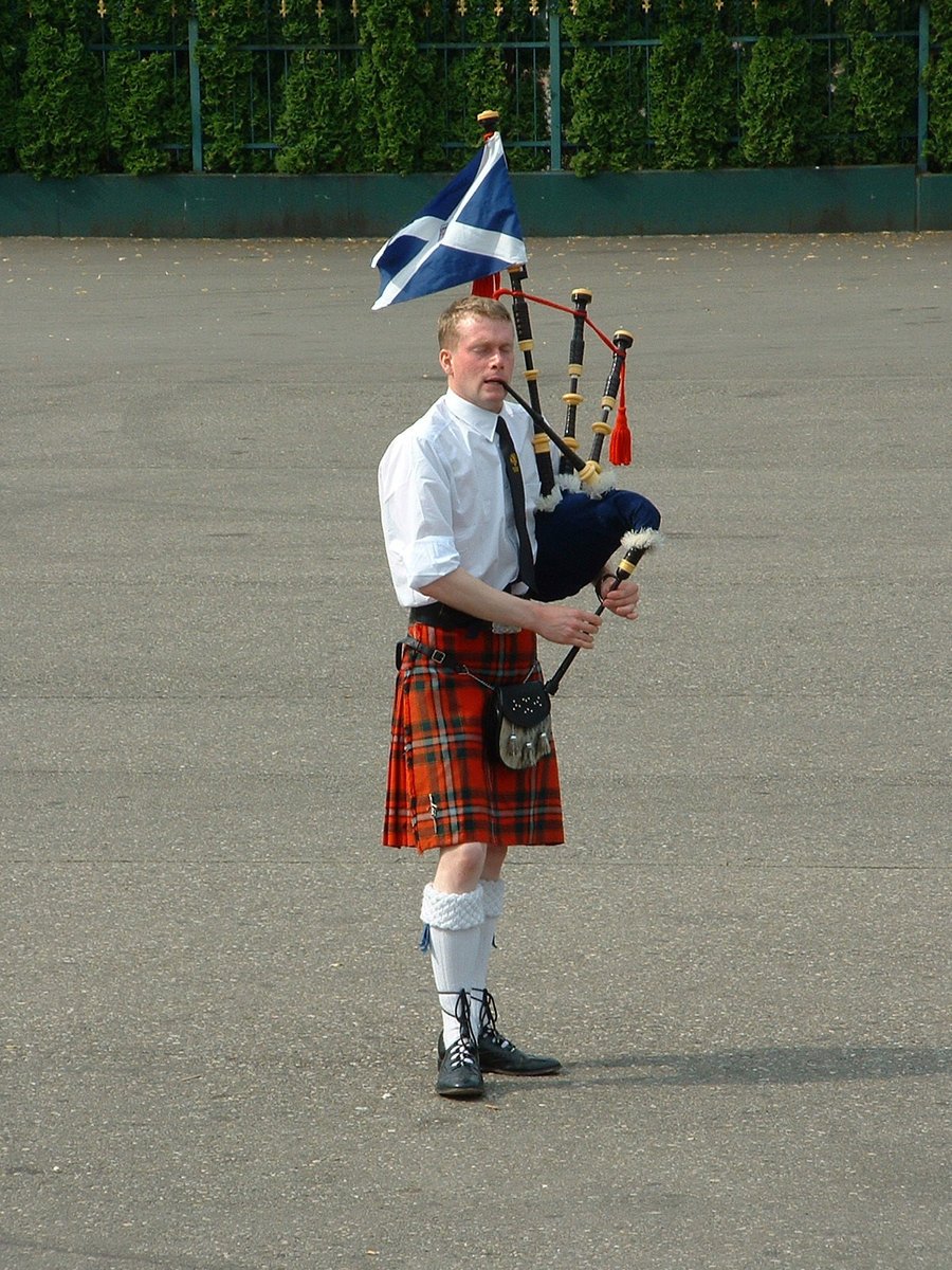 a man holding a bagpipe and a small flag