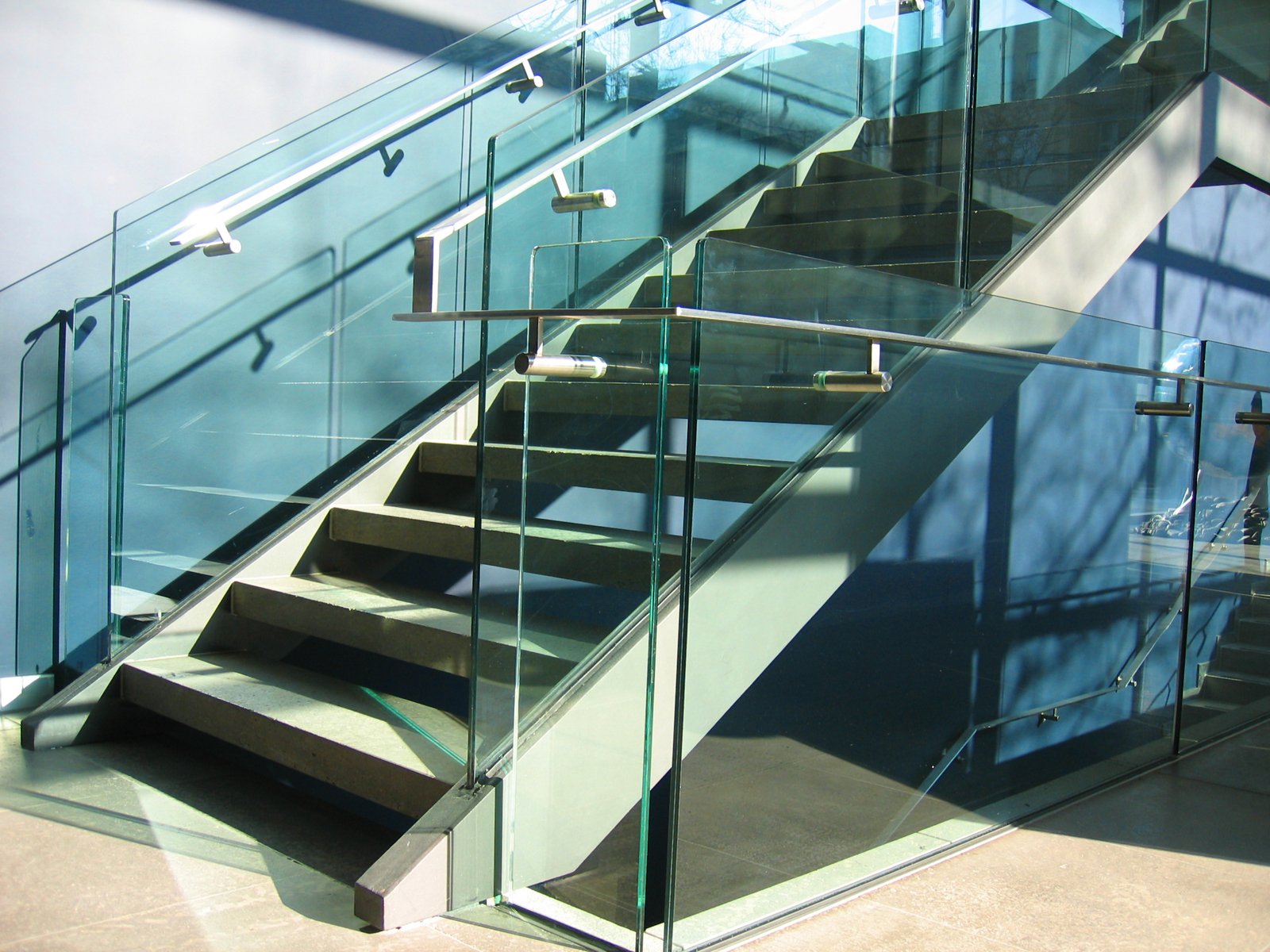 a glass staircase next to a large wall