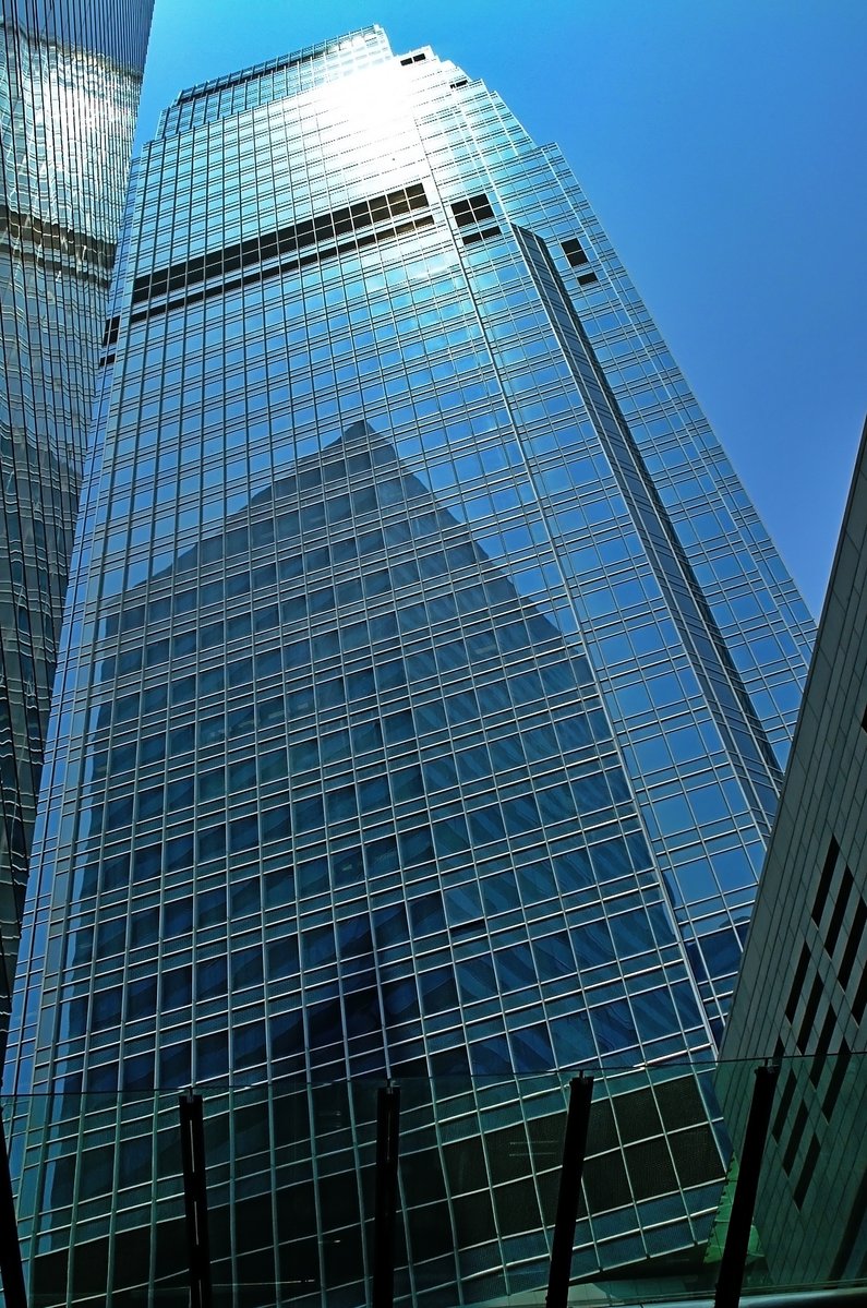 a tall glass building surrounded by other buildings
