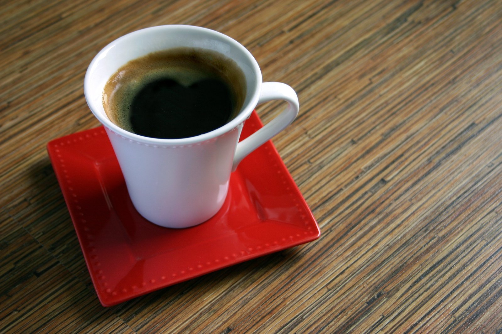 coffee is served in a cup on red coaster