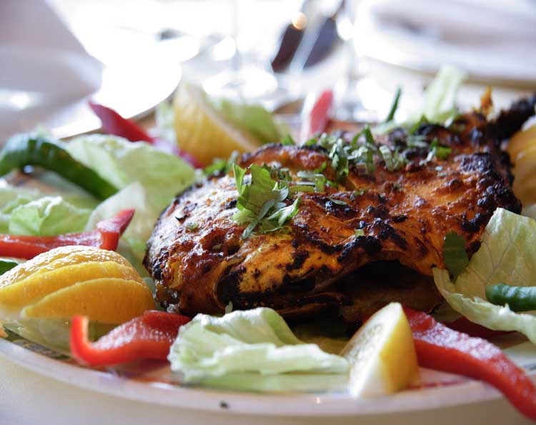 a plate with meat and vegetables on it, including oranges, peppers, and lettuce