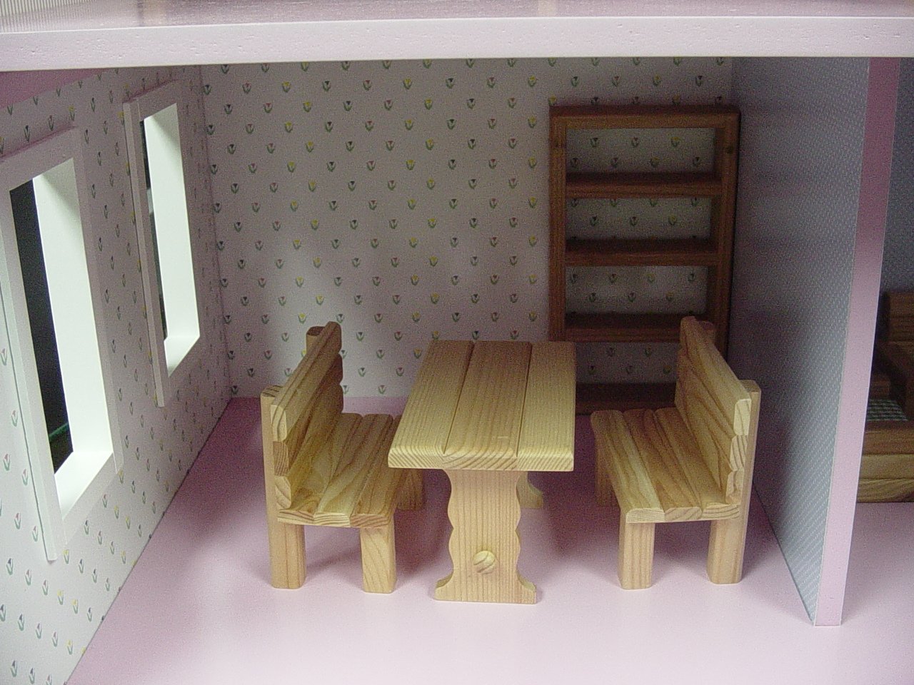 a dollhouse with a table, two benches and a step stool