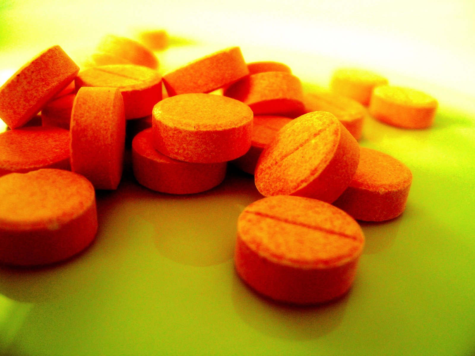 orange pills sitting on a table and yellow background