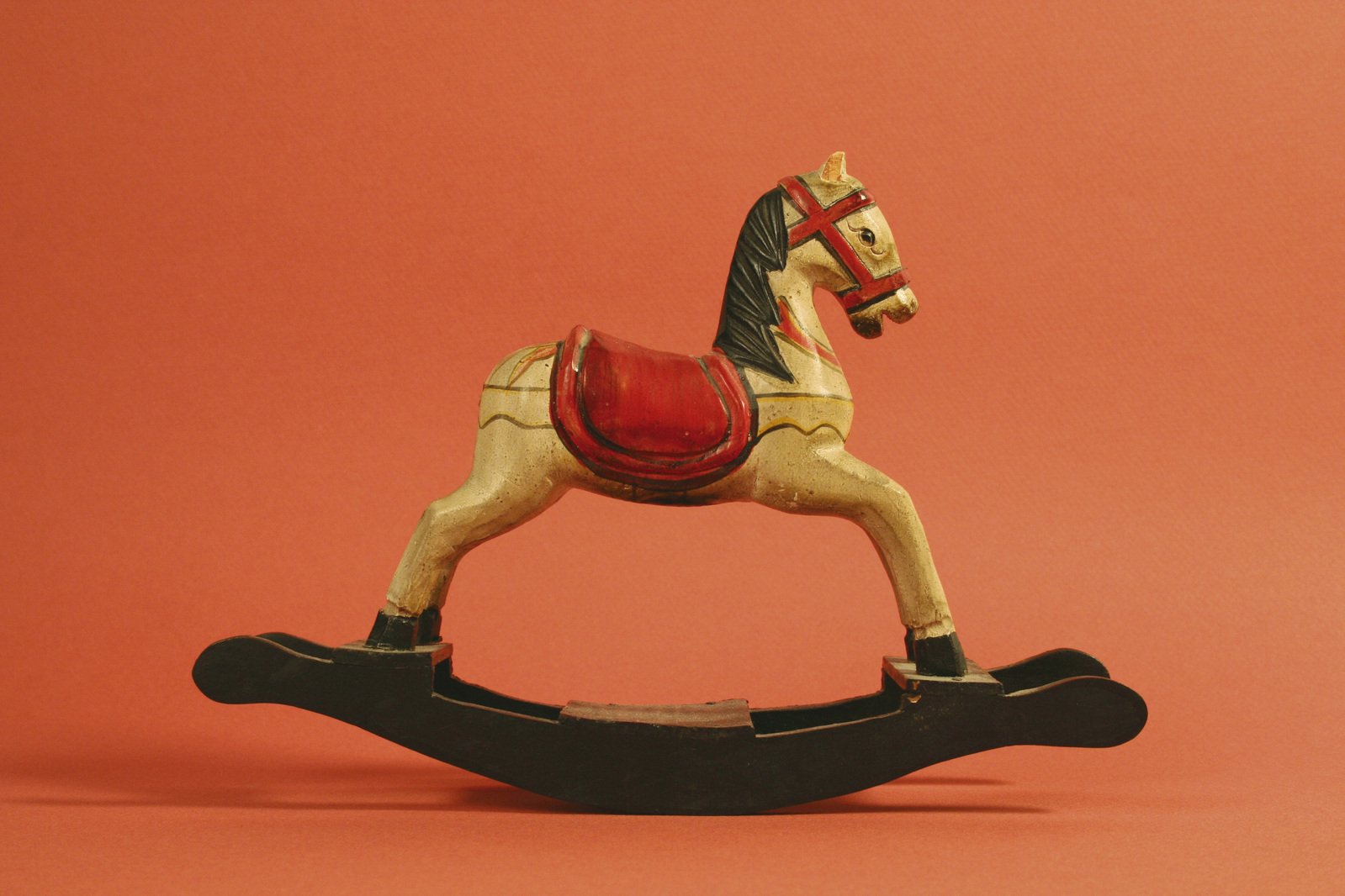 a horse toy standing on it's foot with red and gold accents