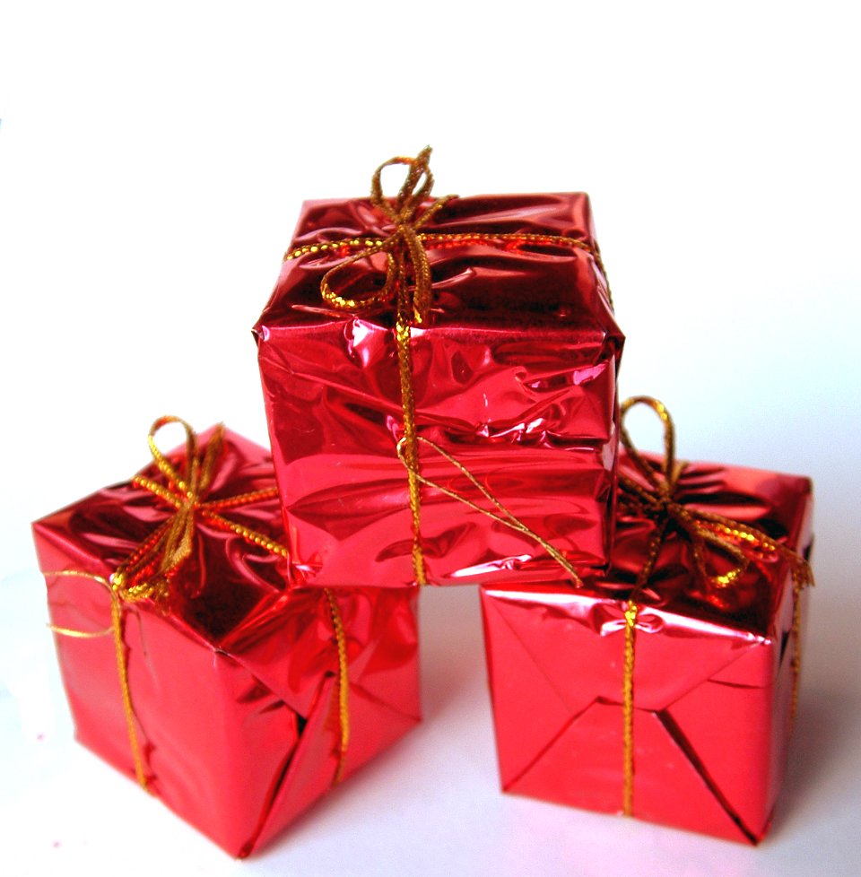 four red presents wrapped in foil sit on a white table