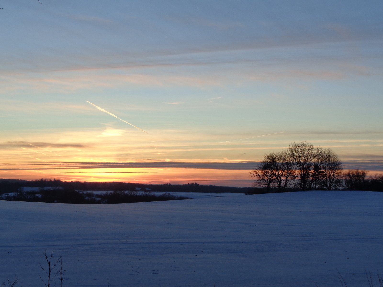 a field covered in snow during a sunset