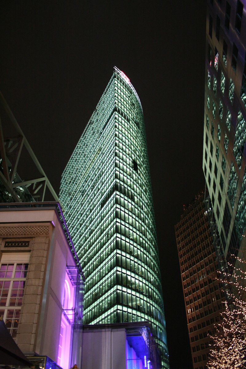 large green lighted skyscr at night with buildings in the background