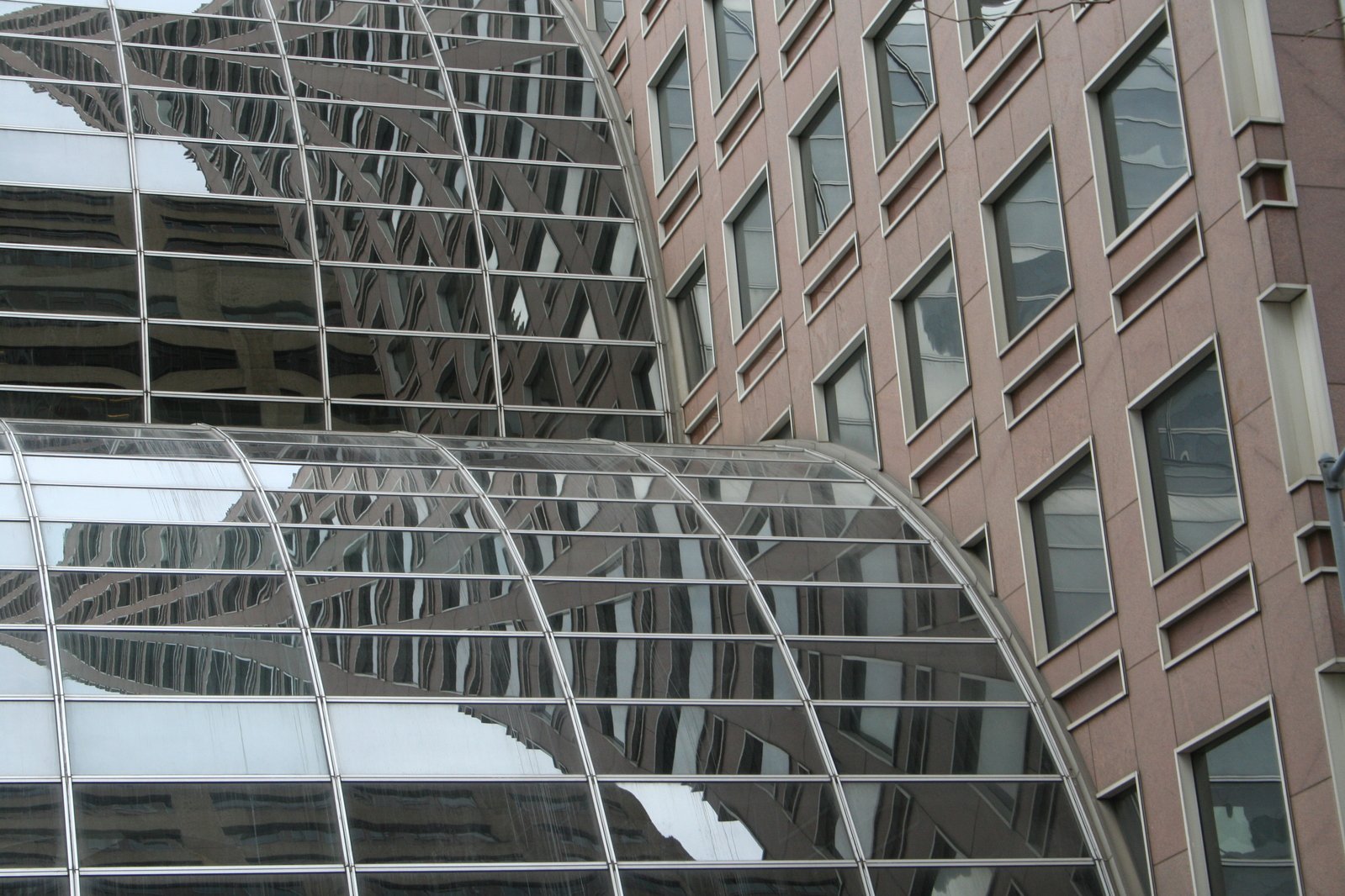 a large mirrored object sitting next to two very tall buildings