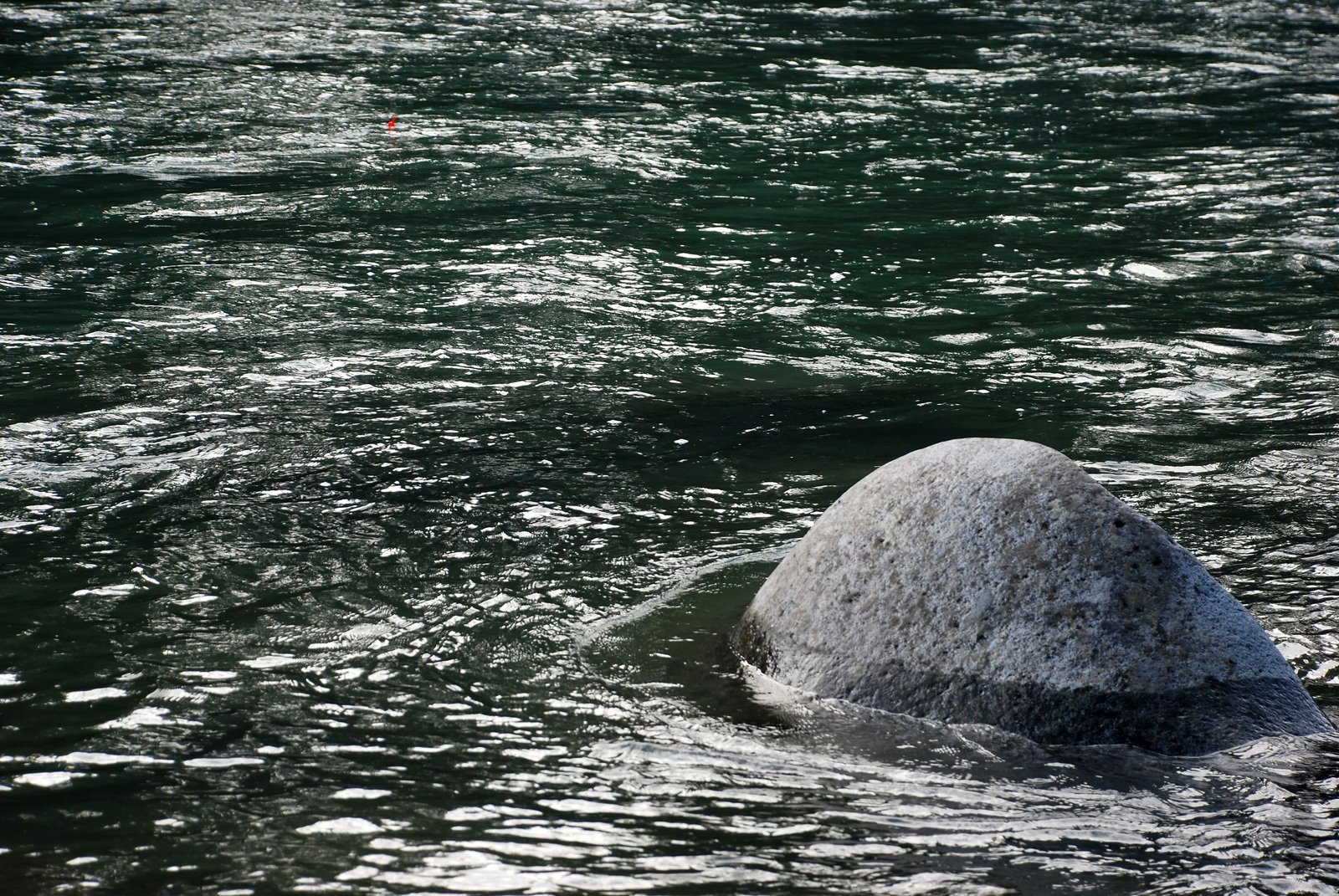 a large rock sticking out of the middle of water