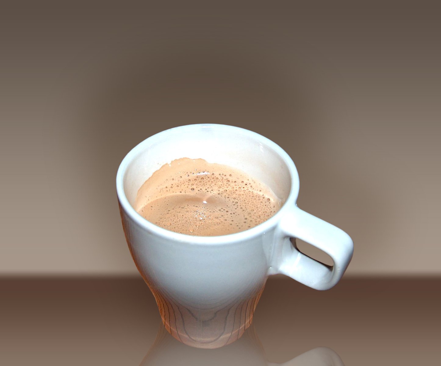 a mug filled with brown liquid next to a white object