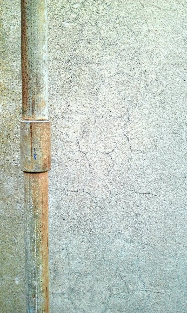 a metal pole next to a concrete wall