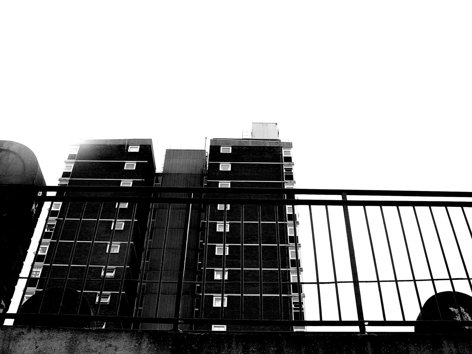 a black and white picture of tall building on a bridge