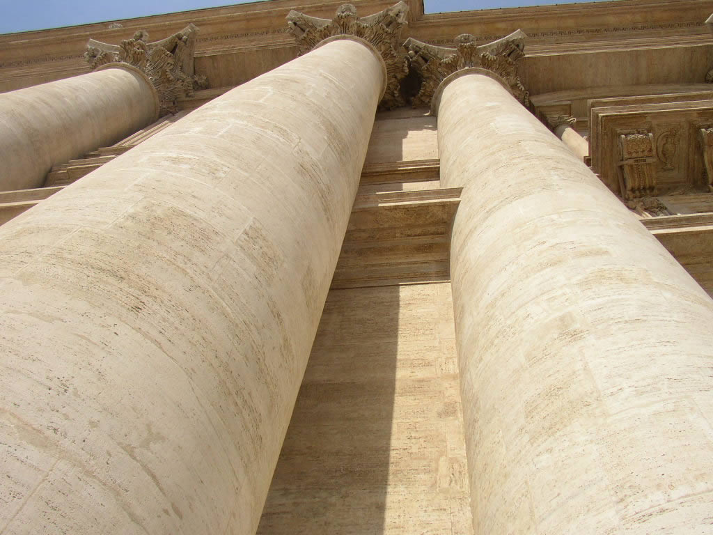 the bottom part of three huge beige columns on a wall