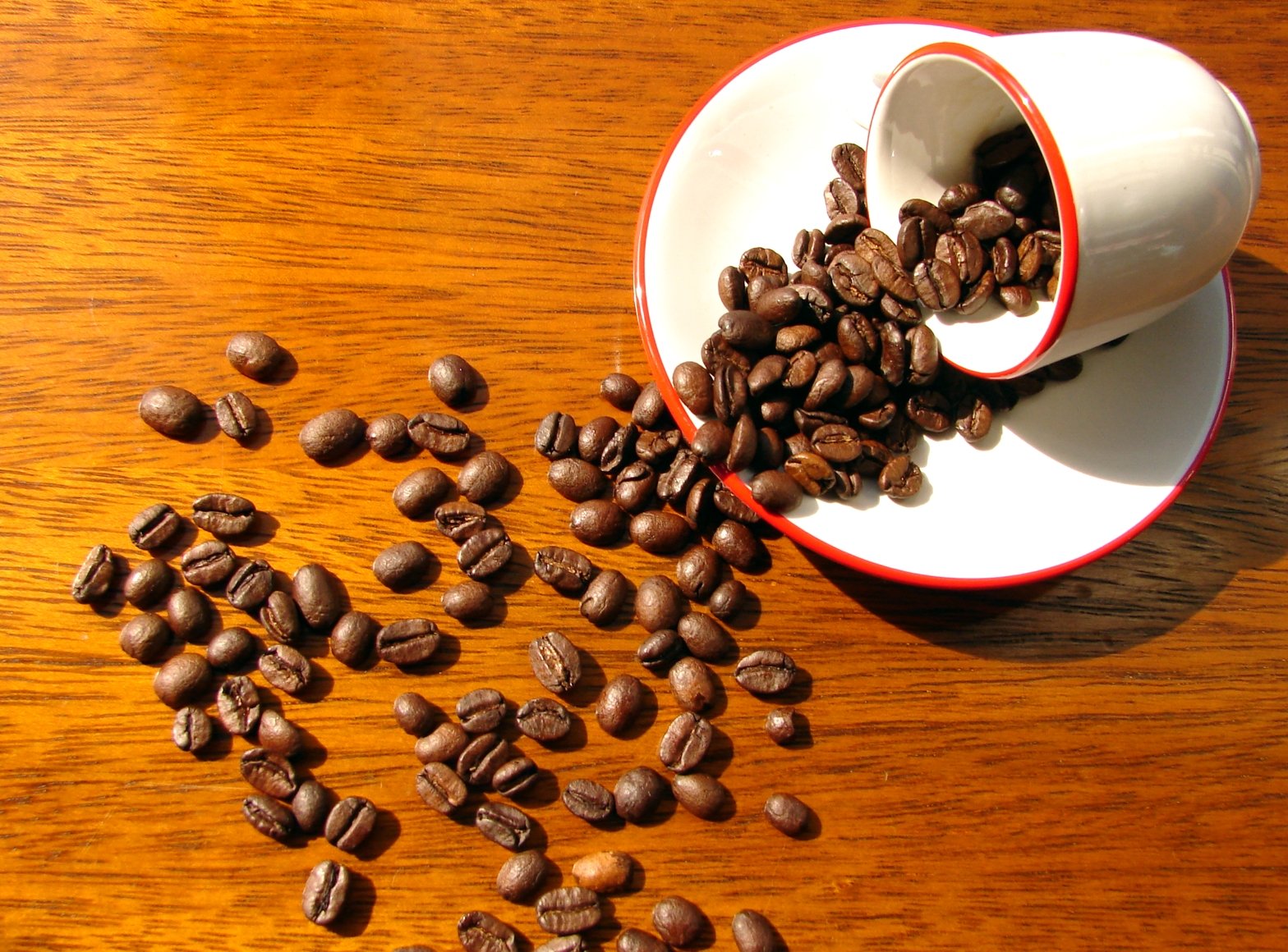 several cups and beans that are spilled on a wooden table