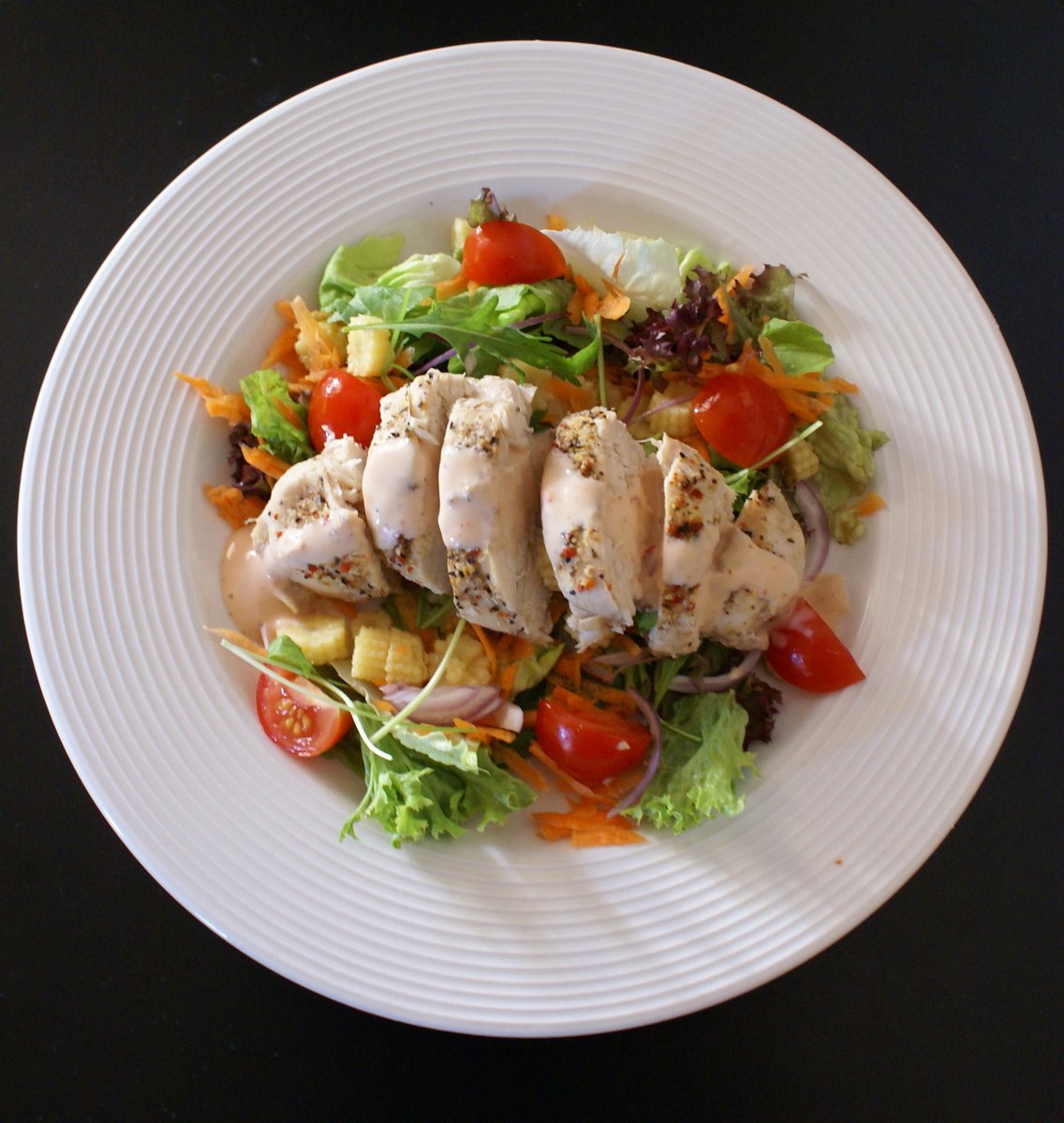 a white plate topped with salad and chicken