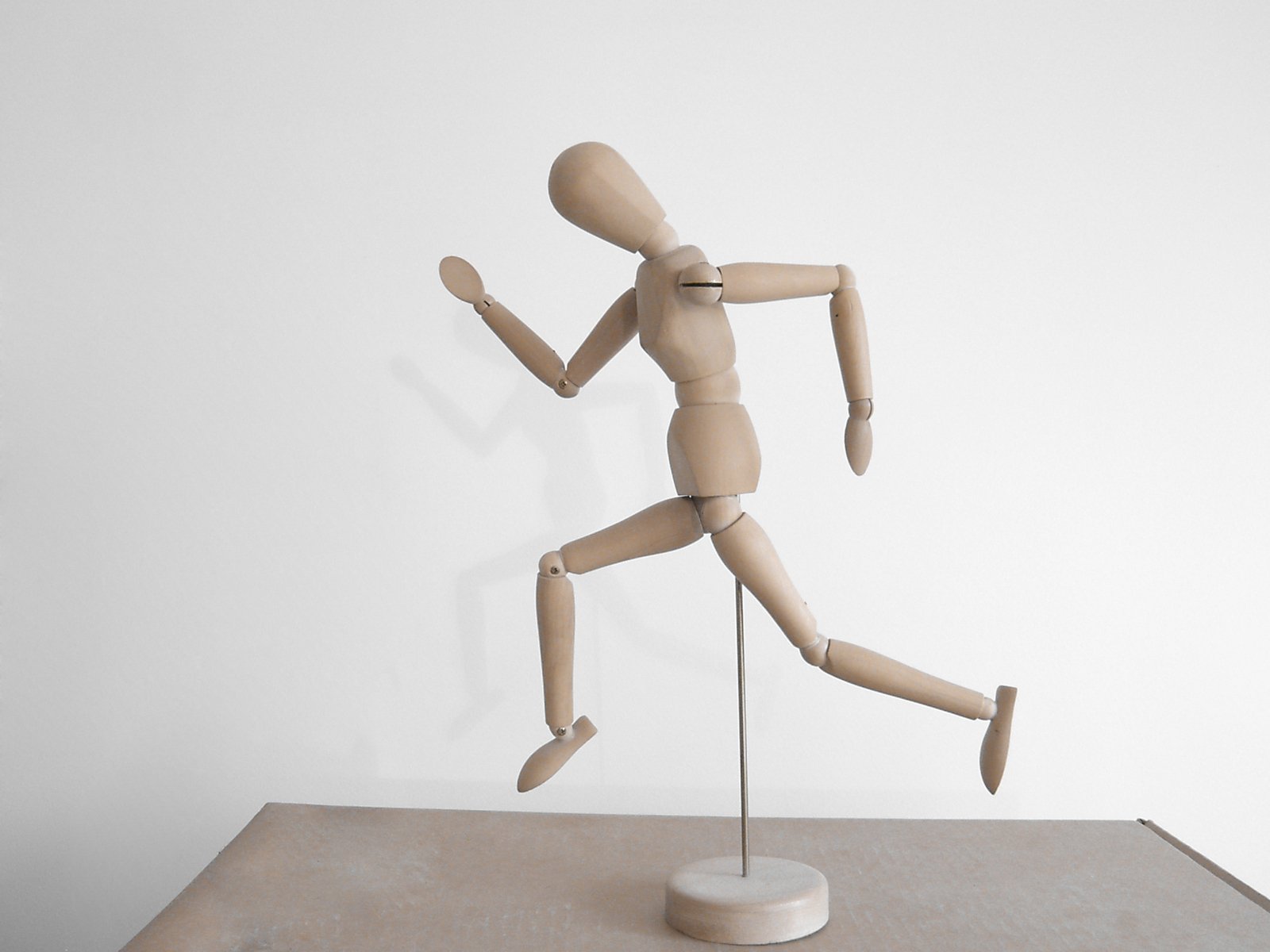 a wooden dummy in front of a white wall