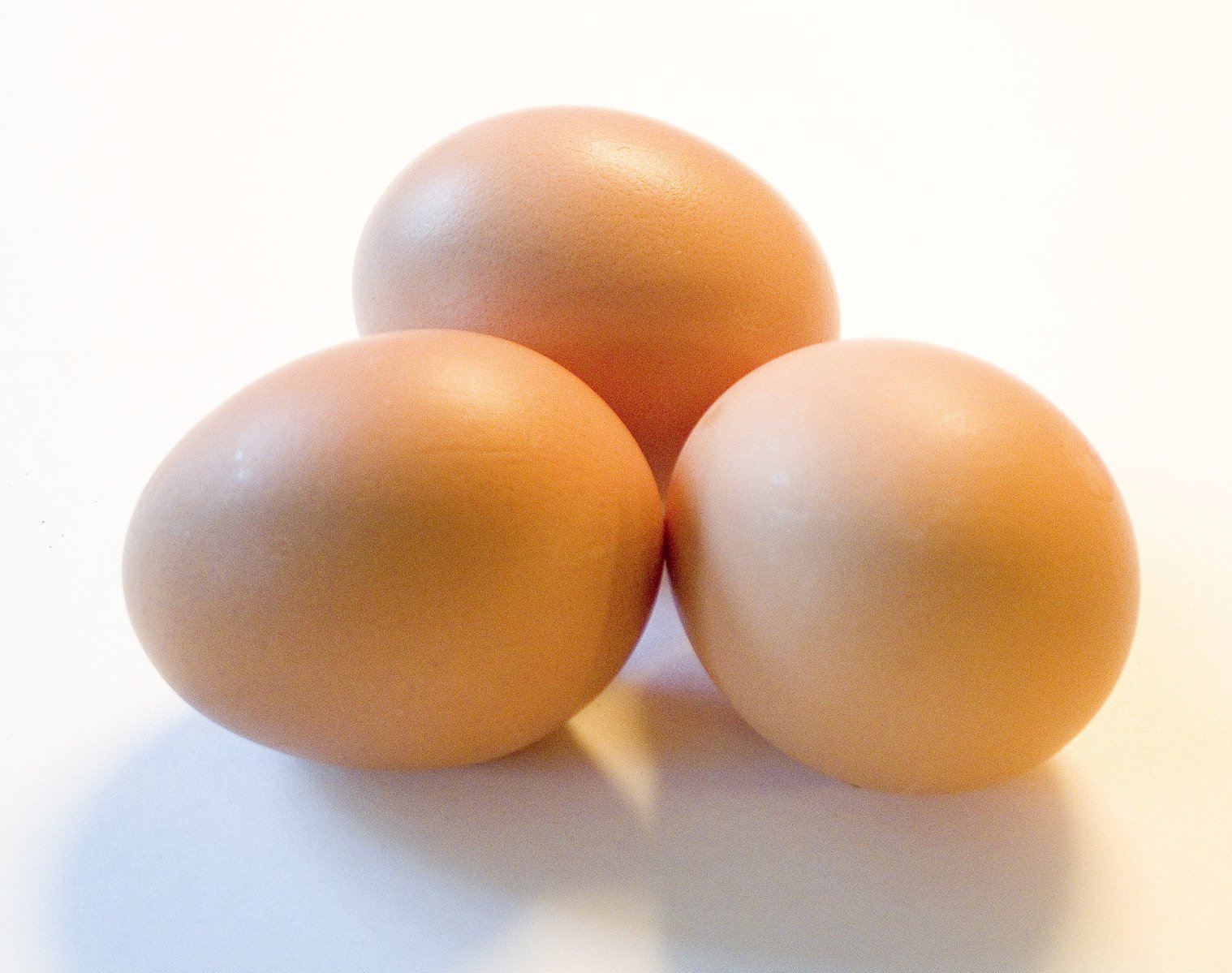three eggs on white background with one yellow and one brown