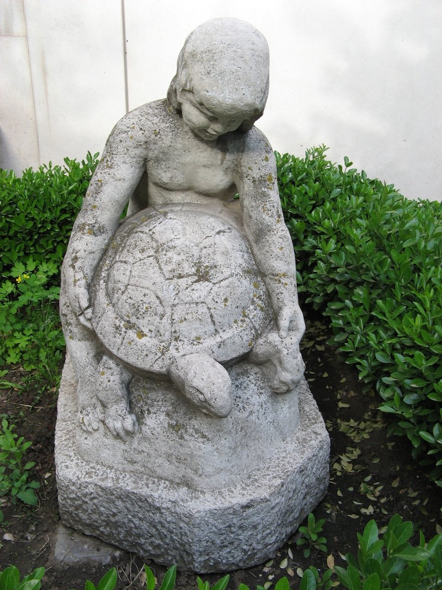 there is a statue of a child that is holding a ball
