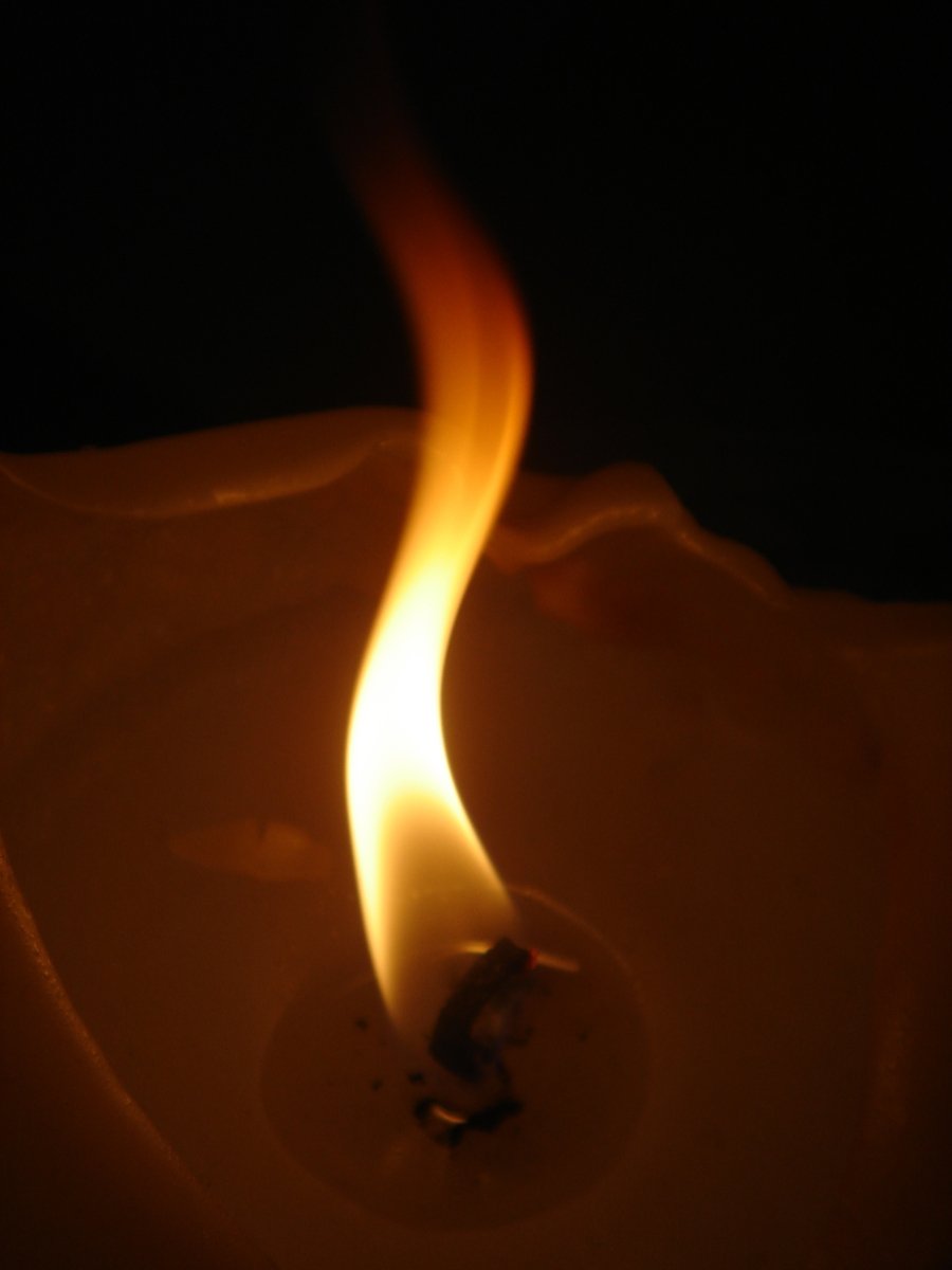 a small lit candle in the dark with a fire running around it