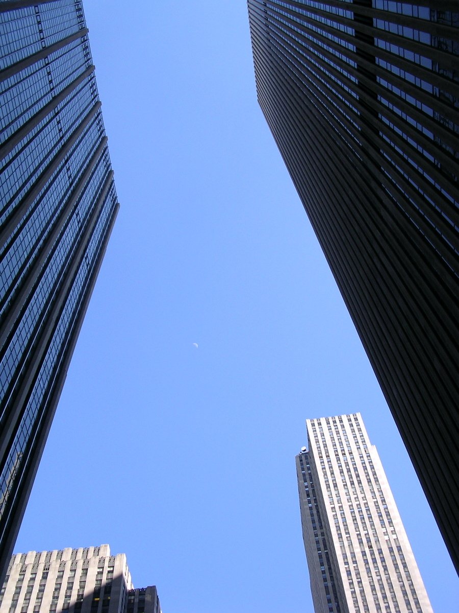 a clear blue sky is seen between two skyscrs