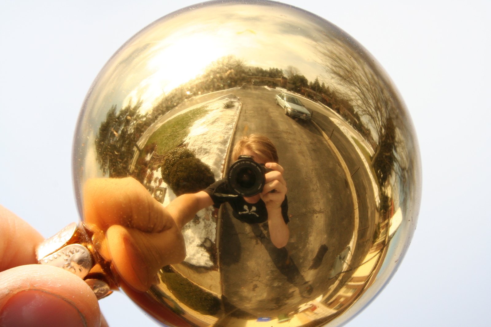 person taking picture through large mirror ball with camera