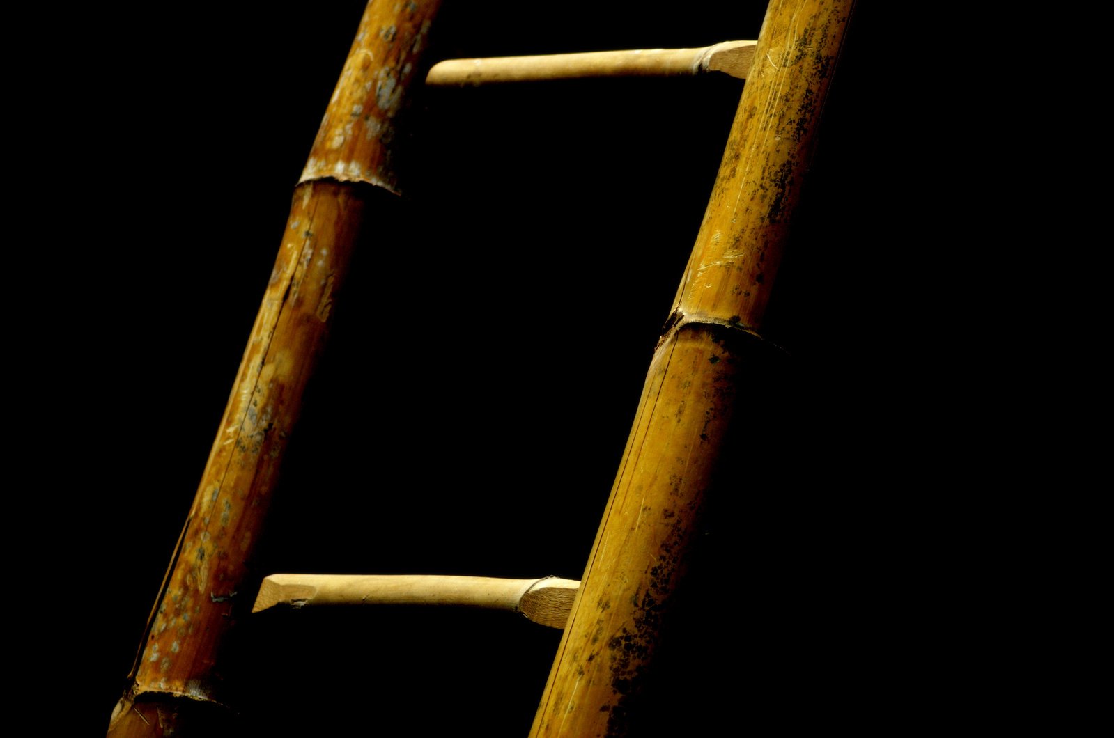 a ladder with rusted paint sits against a dark background