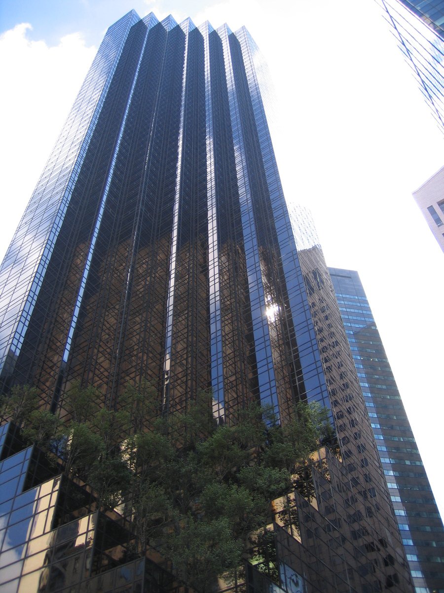 several tall buildings with trees growing around them