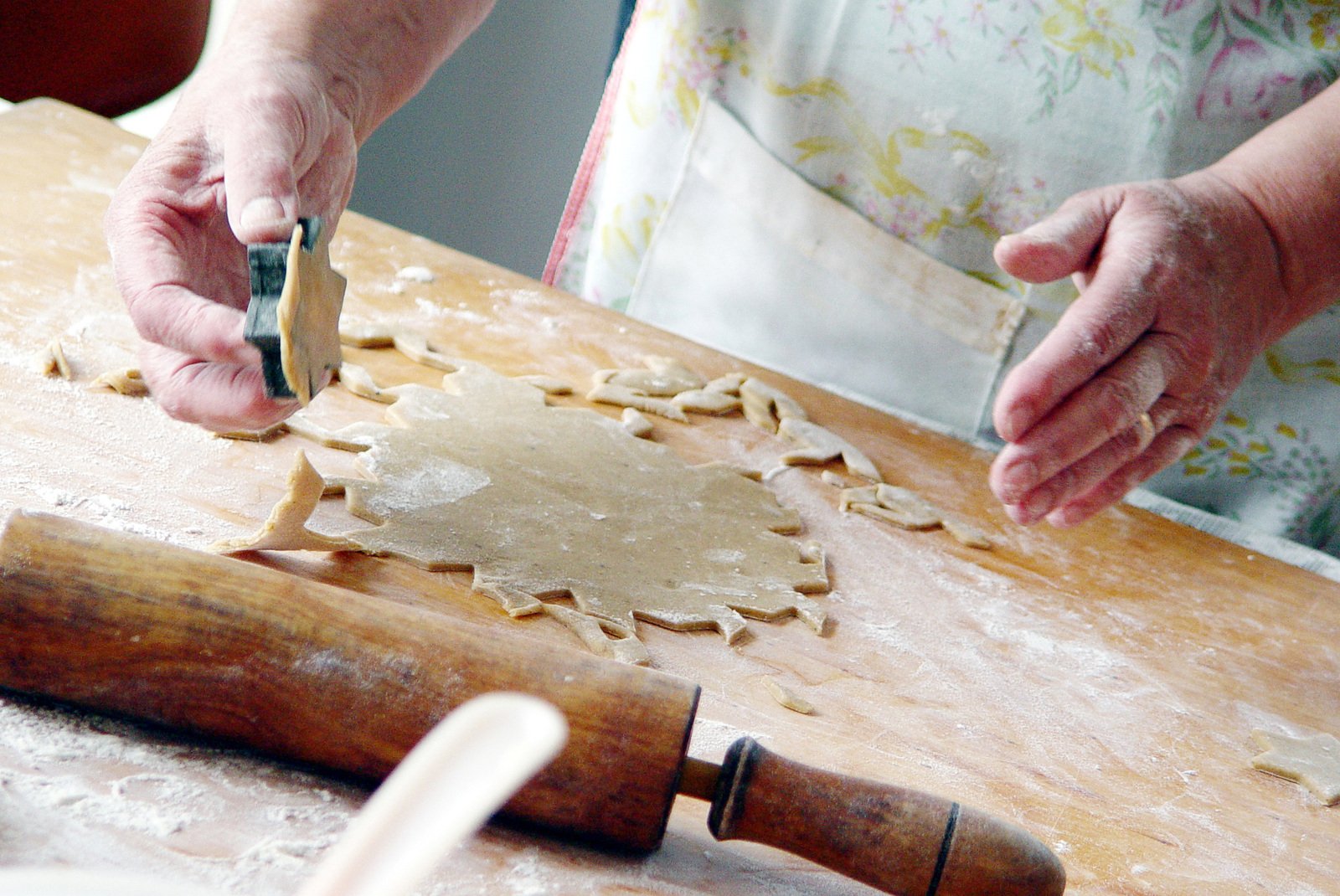 two women making cookies with a manual and rolling dough