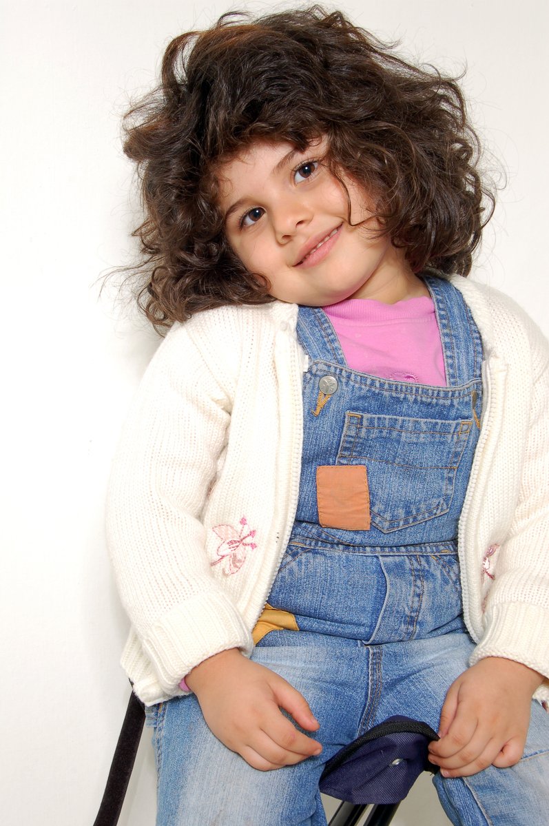 a smiling child wearing overalls and a blue jacket