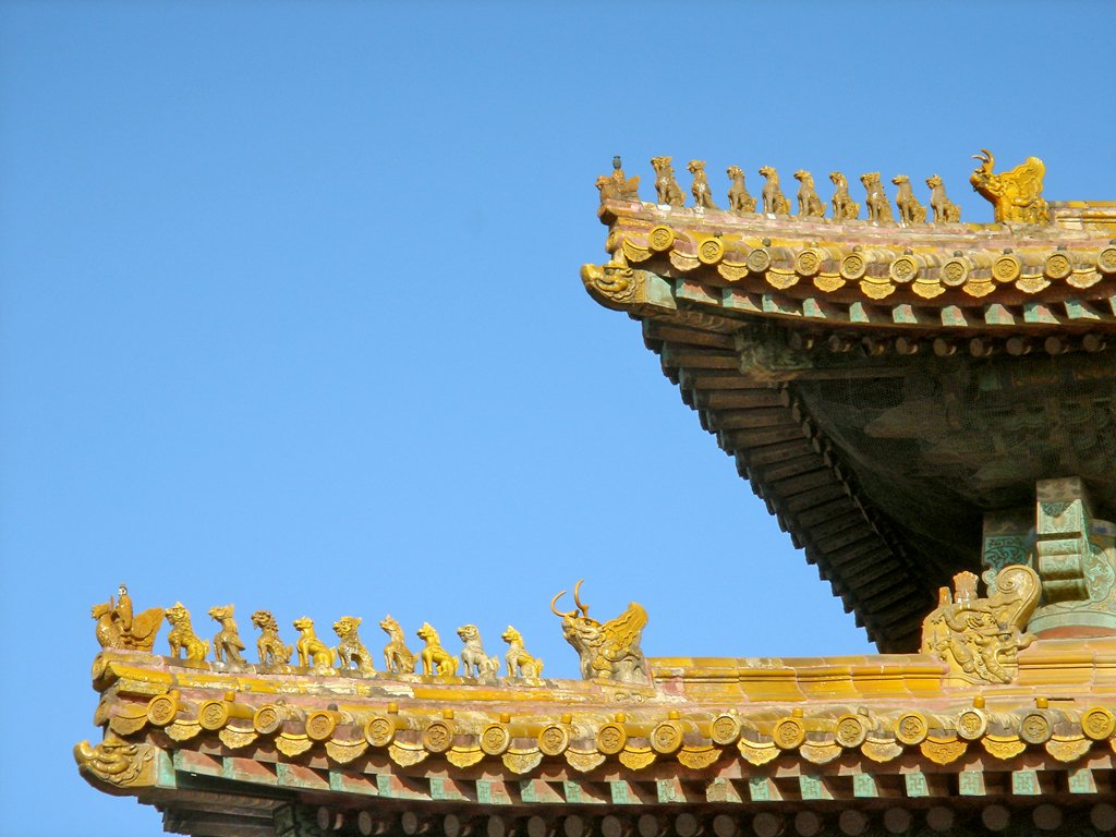 an intricate roof detail with statues against a clear blue sky