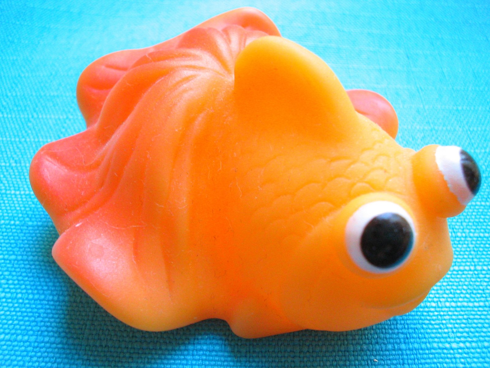 a toy fish with large black eyes on blue fabric