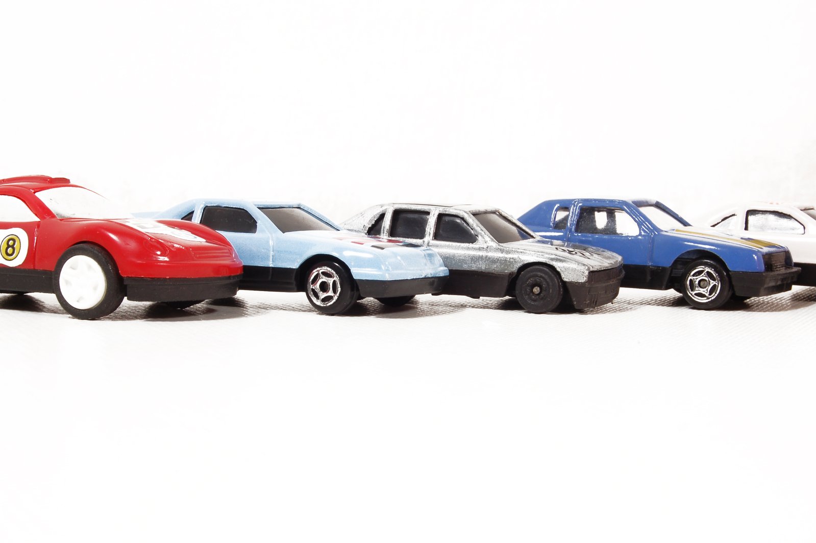 four toy cars sitting side by side, one has the number six on its body