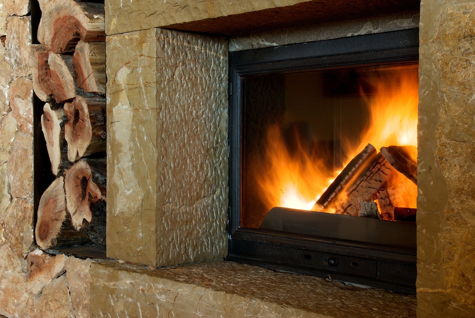 a fireplace burning in a stone hearth covered with logs