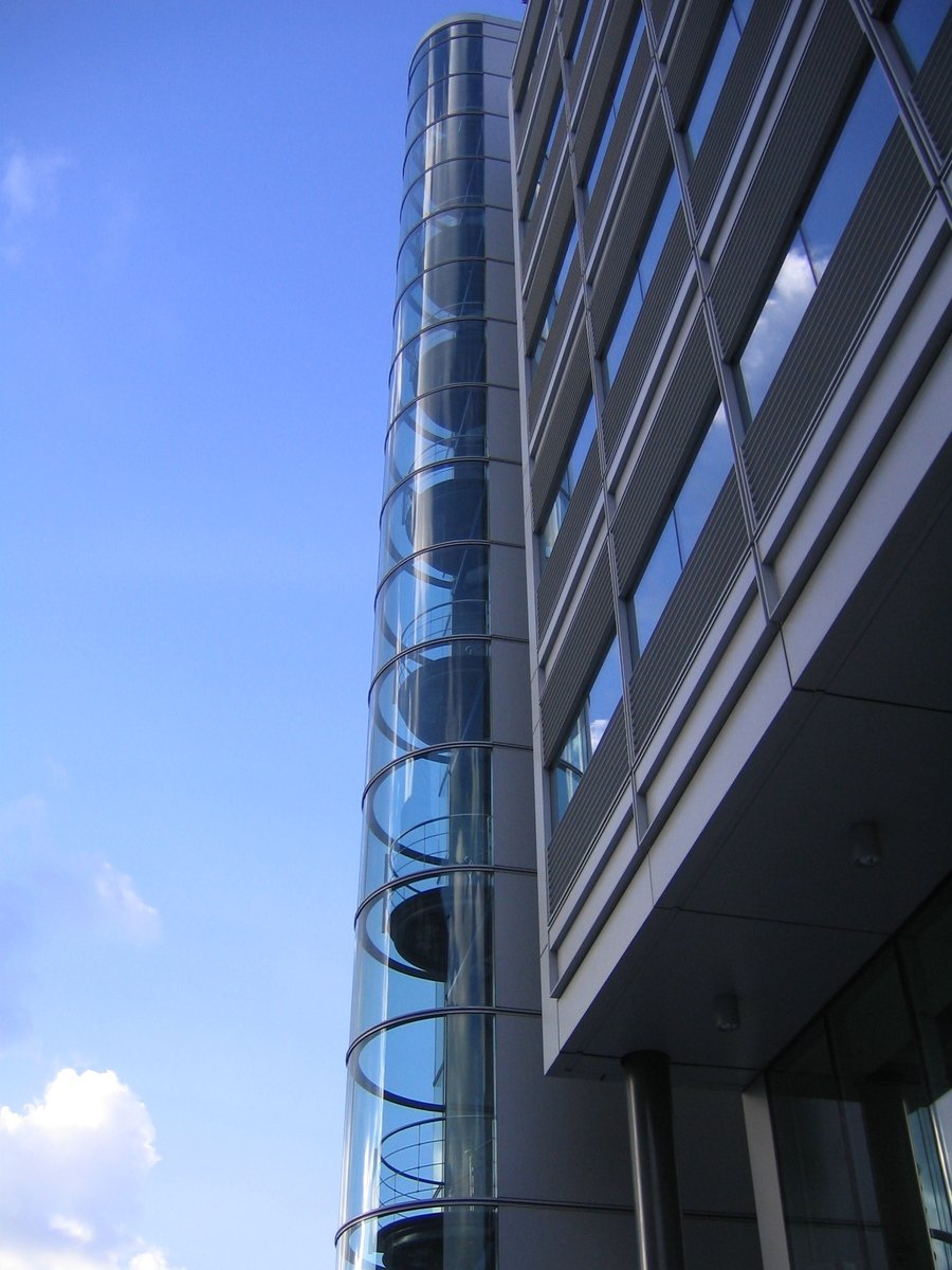 a tall glass building with a traffic signal at the top