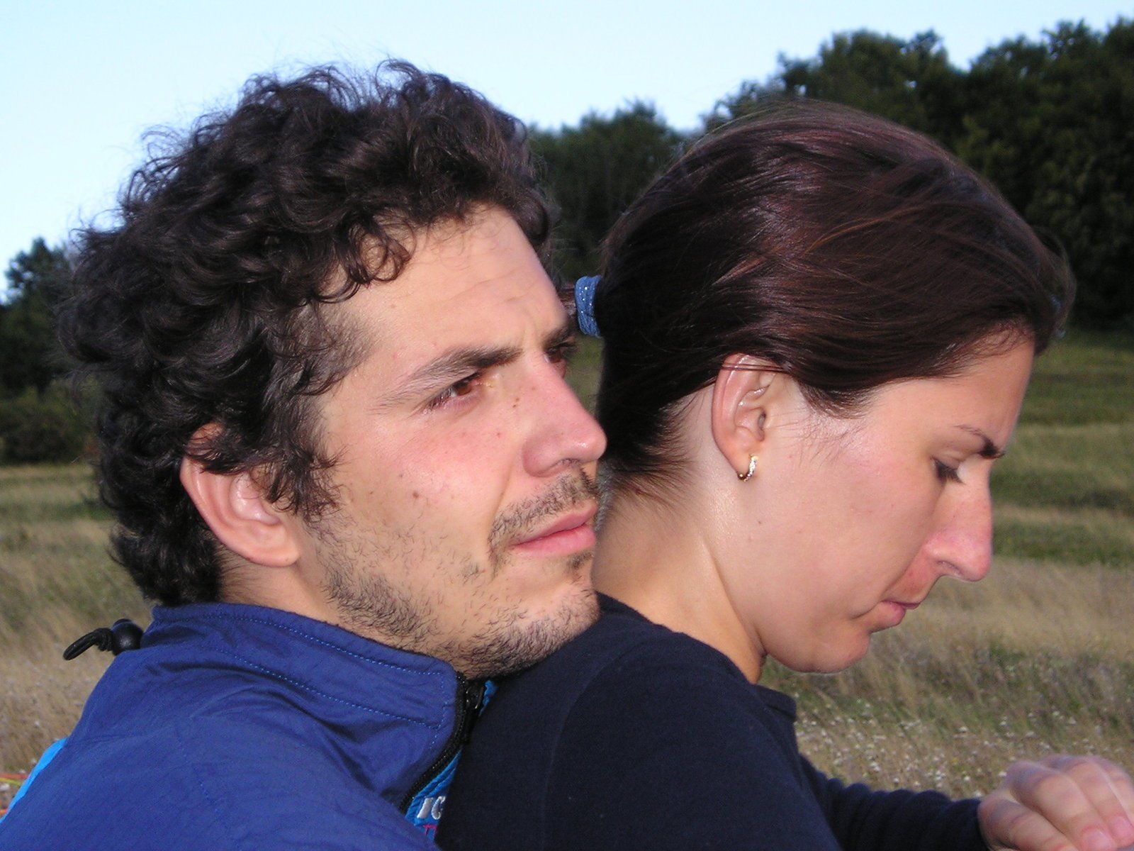 two people standing close to each other in the wild