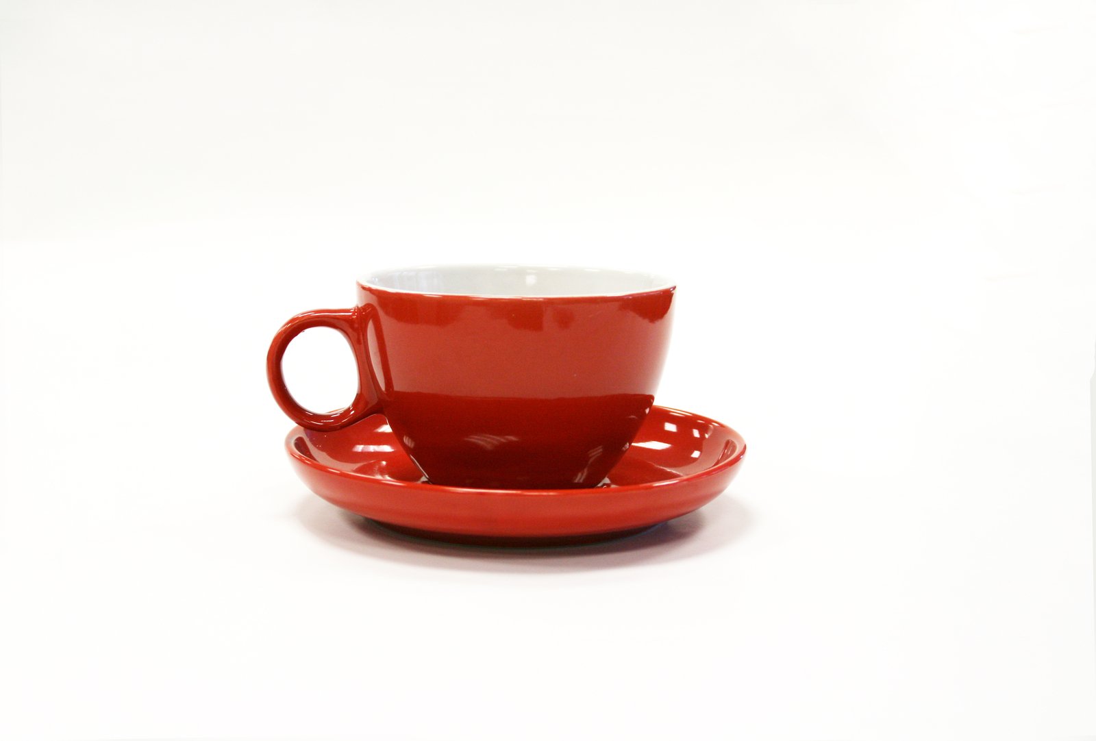 a red cup and saucer with an open plate on top