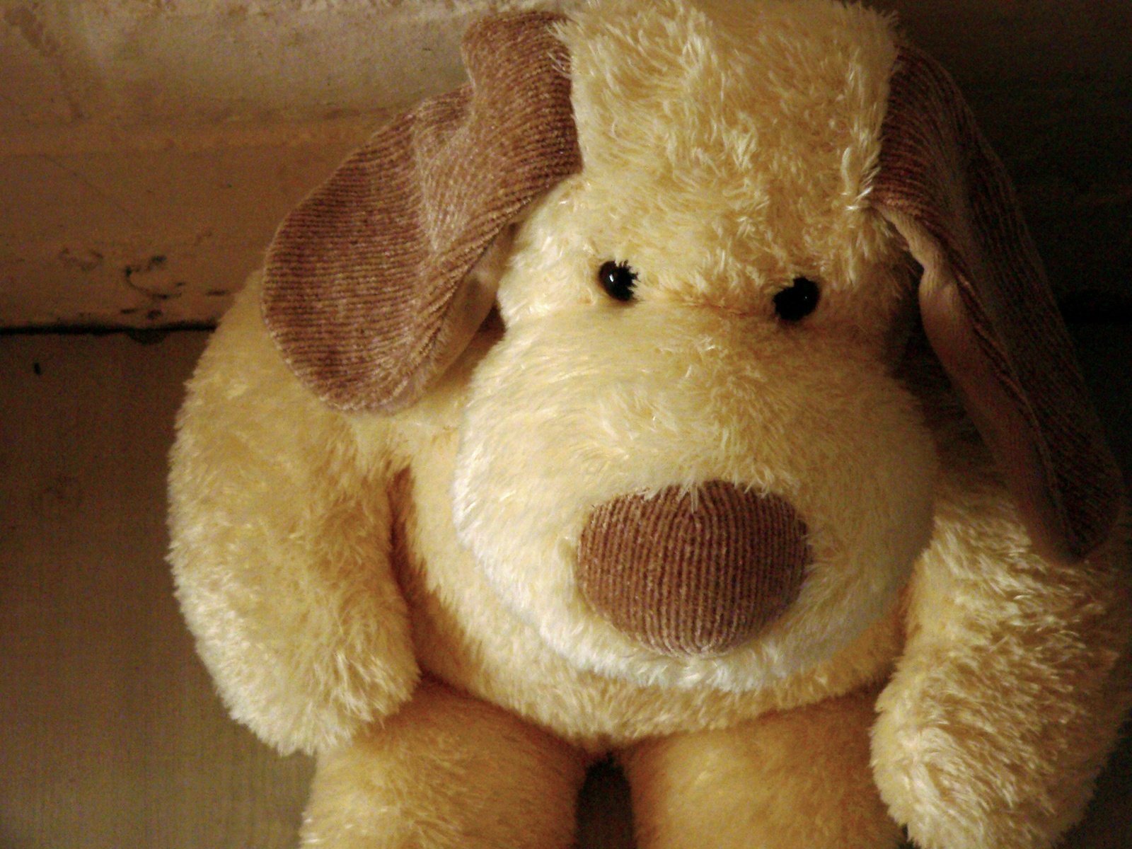 a tan dog shaped stuffed animal on a shelf