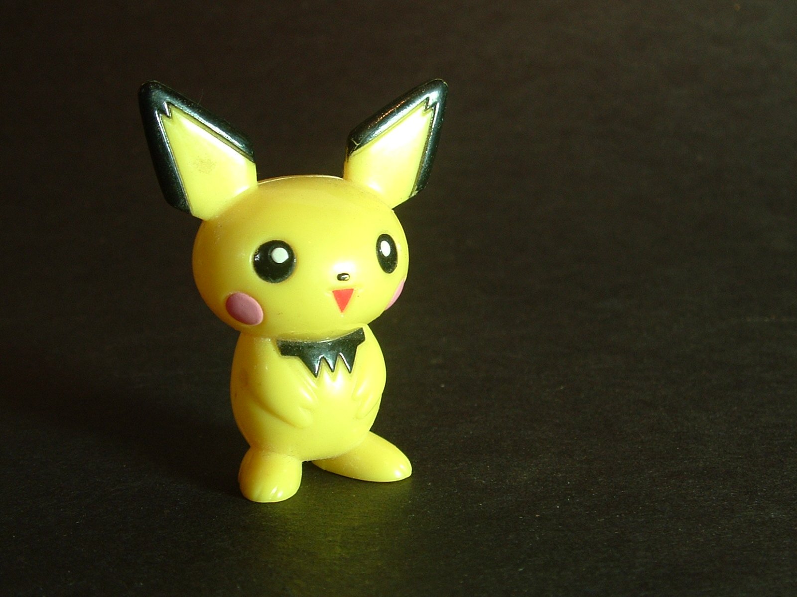 small plastic pikachu with ears standing on black surface