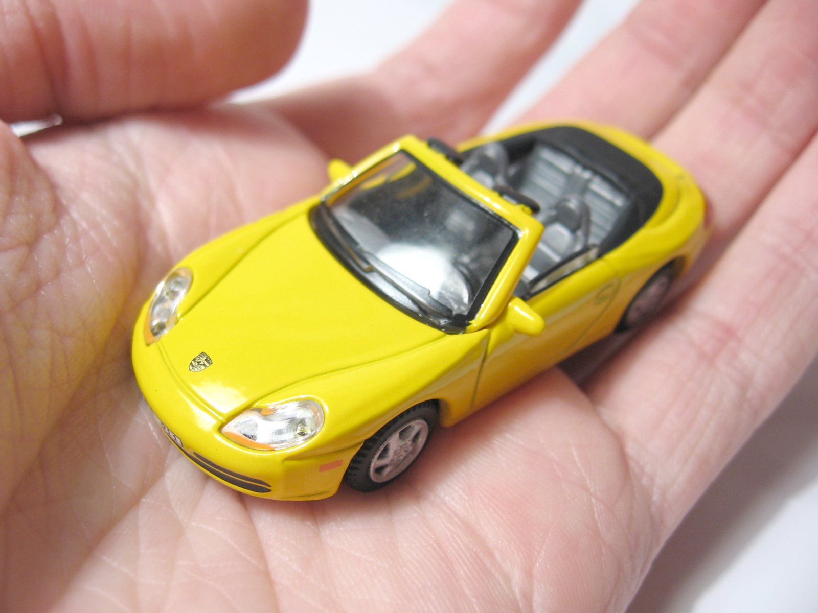 yellow toy car sitting in a palm by itself