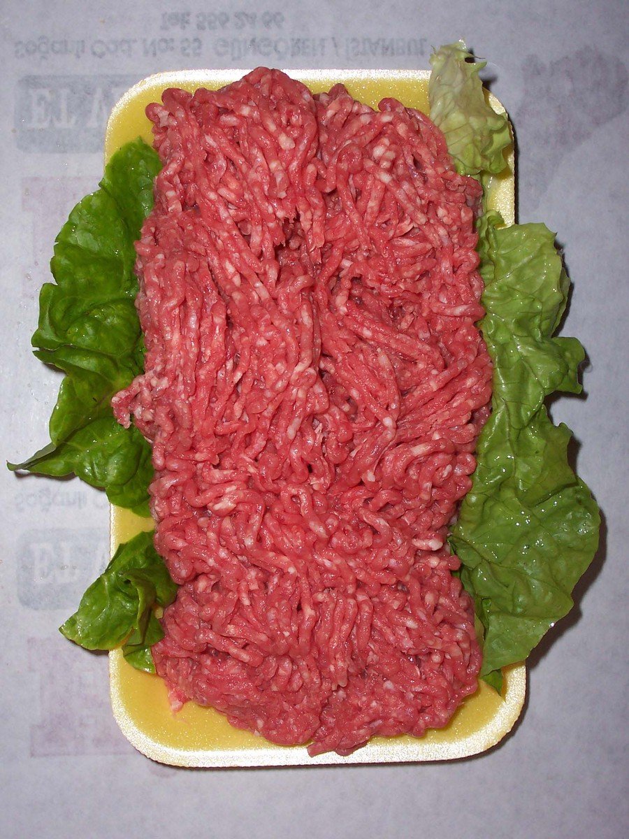 the ground beef is on a plate and it sits on a plate with lettuce