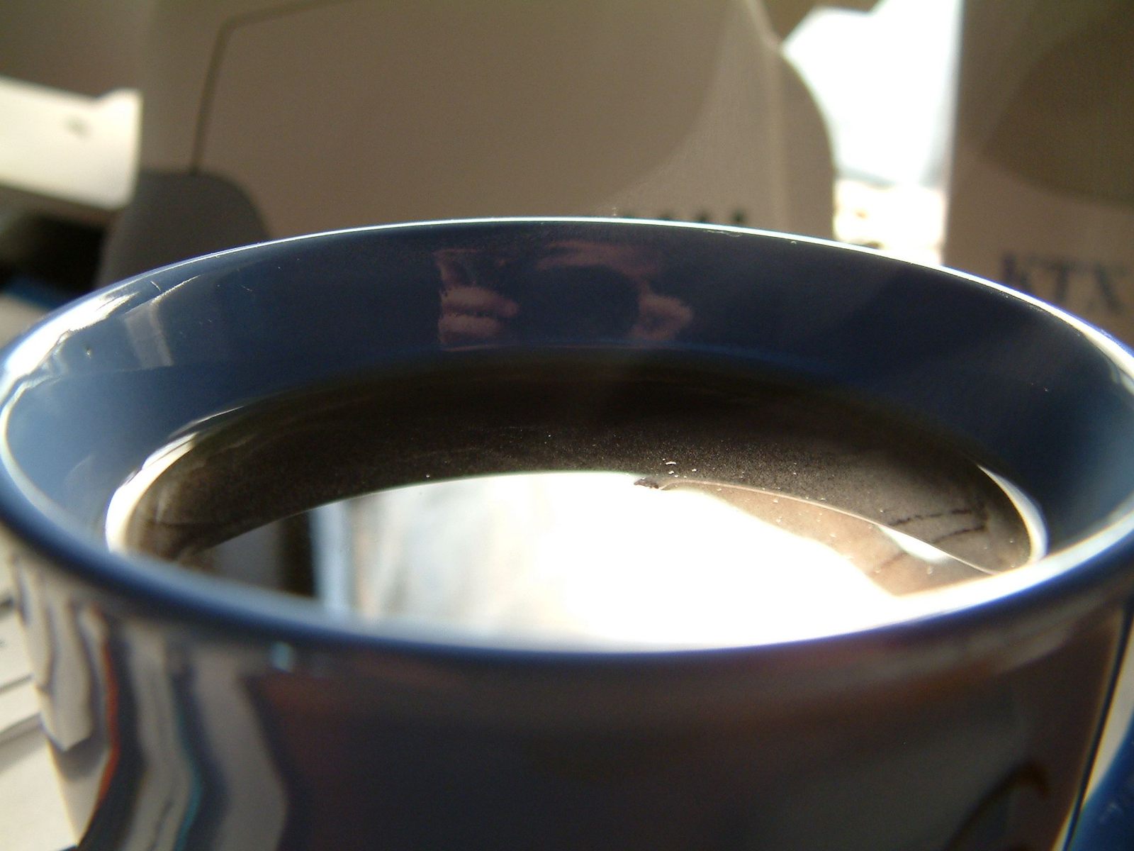 blue glass cup filled with liquid sits on top of a desk